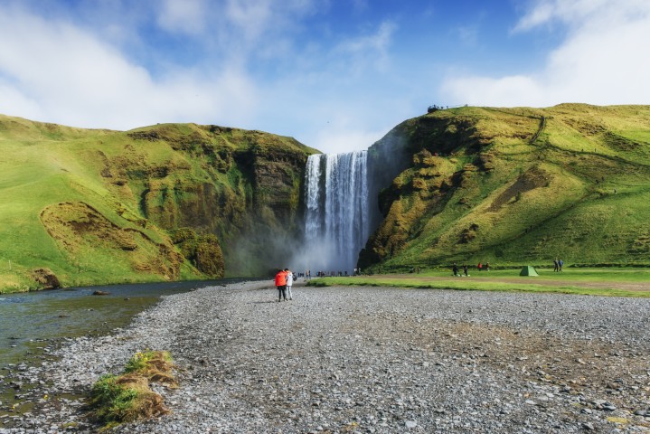 Skogafoss en Islande en pleine journée avec des visiteurs au pied de la cascade